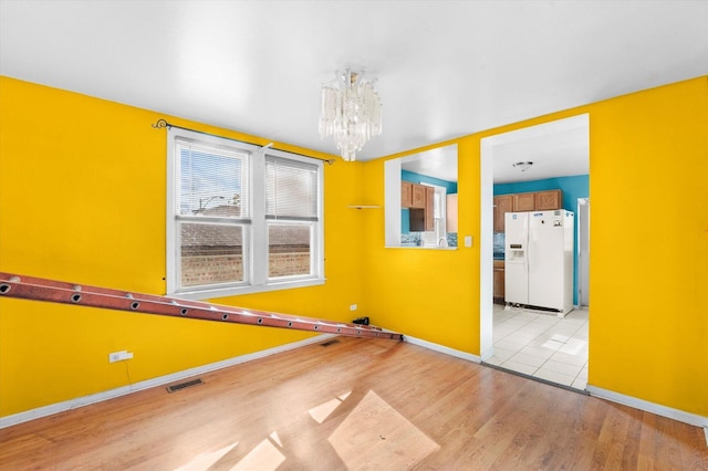 unfurnished room featuring light wood-type flooring and a notable chandelier