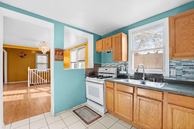 kitchen featuring tasteful backsplash, sink, a notable chandelier, white range with gas stovetop, and light tile patterned flooring