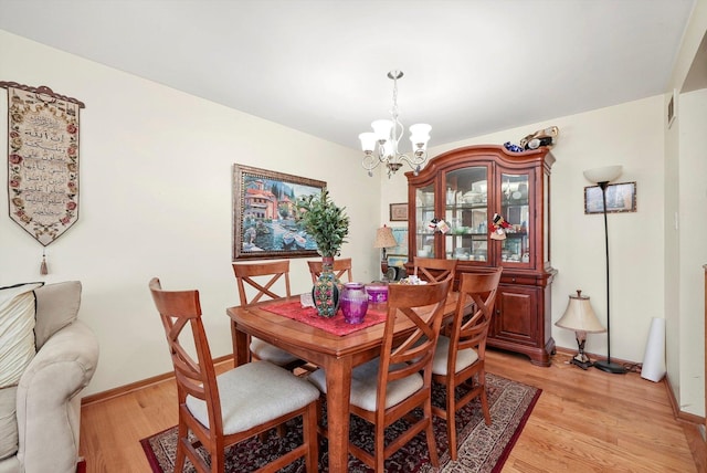 dining space featuring light hardwood / wood-style floors and a chandelier