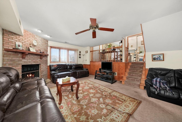 living room with wooden walls, a fireplace, ceiling fan, and light carpet