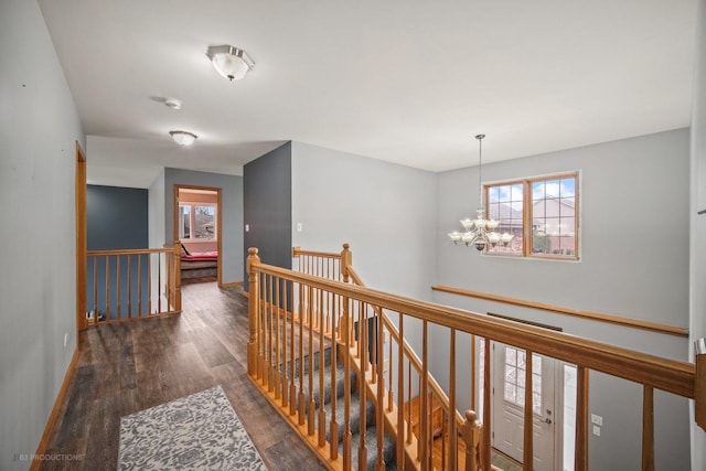 hallway featuring dark wood-type flooring and an inviting chandelier