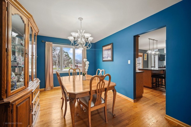 dining area with an inviting chandelier and light hardwood / wood-style flooring