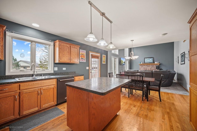 kitchen with dishwasher, a center island, sink, hanging light fixtures, and light hardwood / wood-style flooring