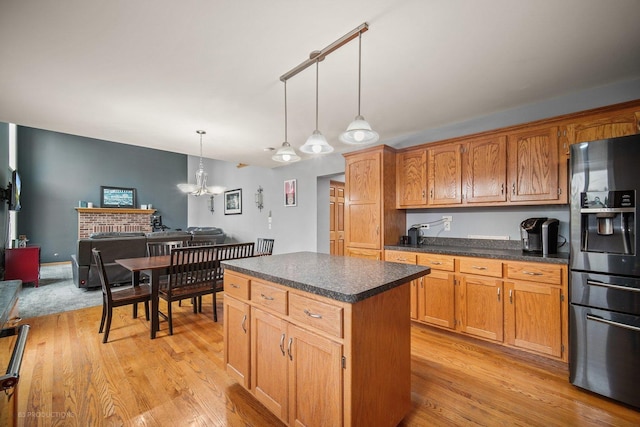 kitchen featuring light wood-type flooring, decorative light fixtures, a kitchen island, and stainless steel fridge