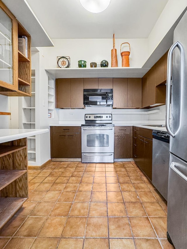 kitchen with dark brown cabinetry, light tile patterned floors, and stainless steel appliances