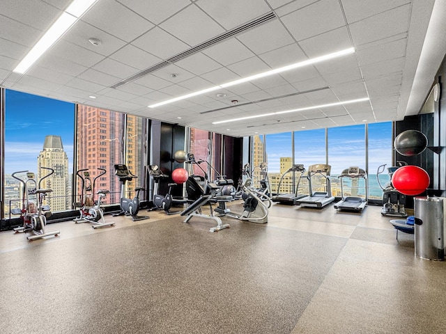 workout area with a paneled ceiling, a water view, and expansive windows