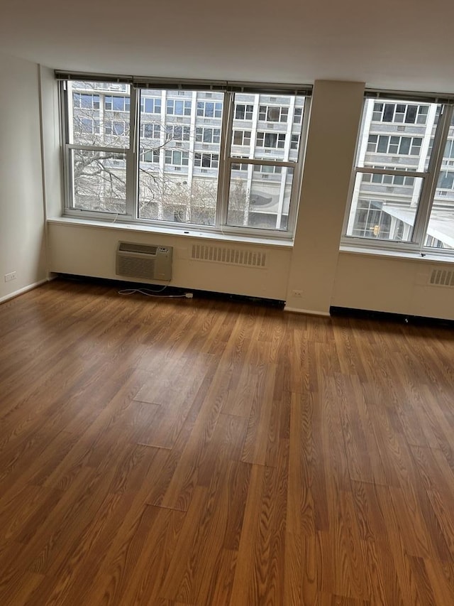 empty room with hardwood / wood-style floors, a healthy amount of sunlight, and a wall mounted AC