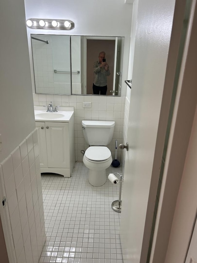 bathroom with tile patterned flooring, vanity, toilet, and tile walls