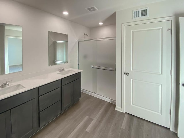 bathroom with hardwood / wood-style floors, vanity, and a shower with door