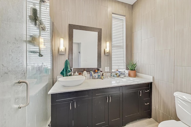 bathroom with vanity, toilet, tile walls, and walk in shower