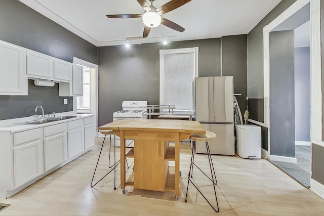 kitchen featuring stainless steel fridge, sink, white cabinetry, and white stove