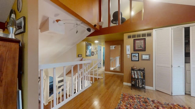 corridor with vaulted ceiling with beams and light hardwood / wood-style floors