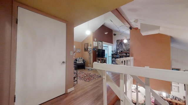 corridor with hardwood / wood-style floors and high vaulted ceiling