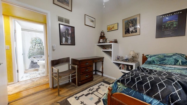 bedroom featuring ensuite bath and hardwood / wood-style floors