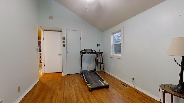 exercise room featuring light hardwood / wood-style floors and lofted ceiling