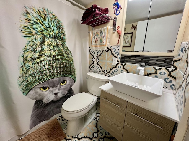 bathroom featuring vanity, toilet, and tasteful backsplash