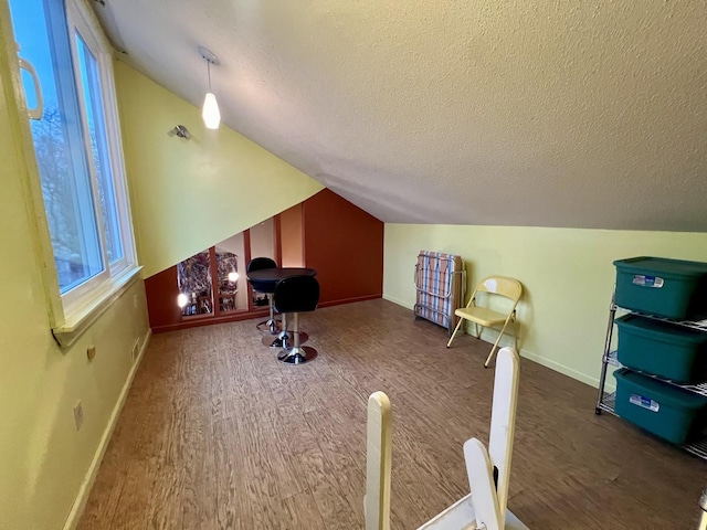 bonus room featuring a textured ceiling, dark hardwood / wood-style floors, and vaulted ceiling