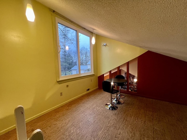 bonus room with hardwood / wood-style floors and a textured ceiling