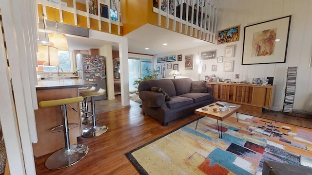 living room featuring a high ceiling, sink, and hardwood / wood-style floors