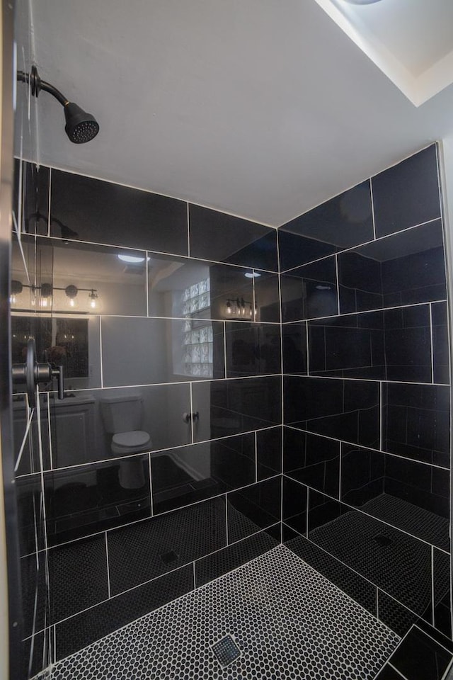 bathroom with tiled shower and toilet