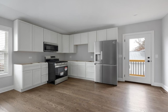 kitchen with appliances with stainless steel finishes, light wood-type flooring, and white cabinets