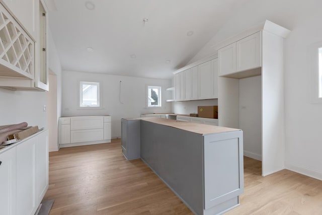 kitchen featuring white cabinetry, vaulted ceiling, a center island, and light hardwood / wood-style flooring