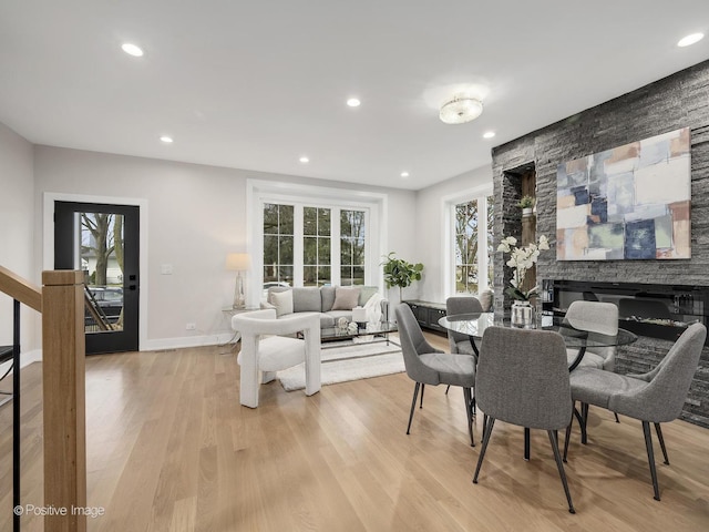 dining room featuring light hardwood / wood-style flooring and a stone fireplace