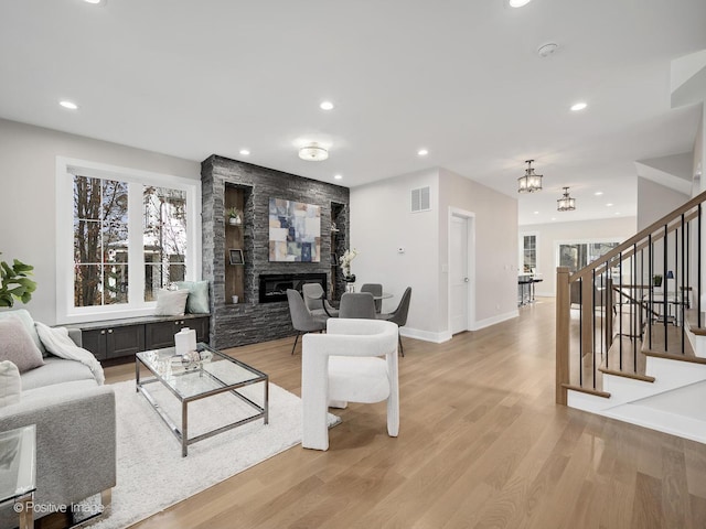 living room featuring a fireplace, light wood-type flooring, and a notable chandelier