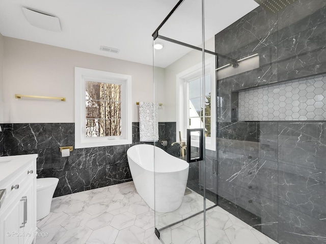 full bathroom with tile walls, toilet, vanity, and independent shower and bath