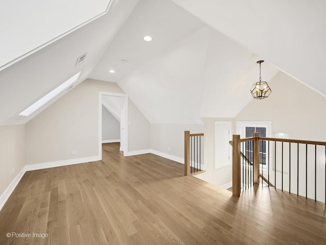 bonus room featuring vaulted ceiling with skylight and hardwood / wood-style floors