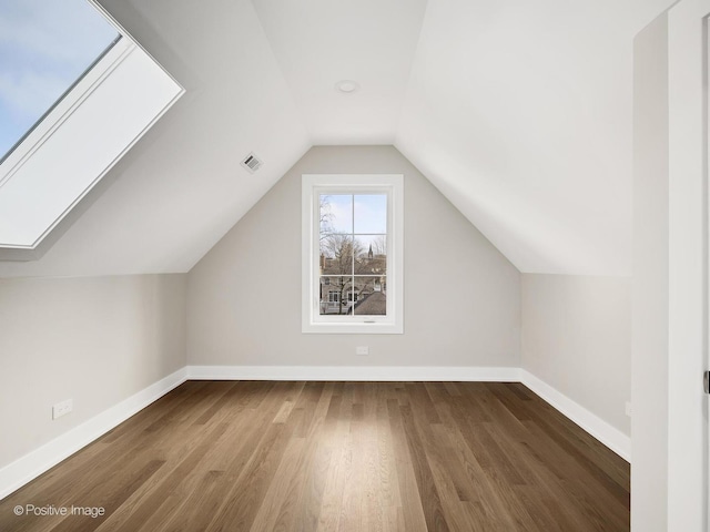 bonus room featuring dark hardwood / wood-style floors and lofted ceiling with skylight