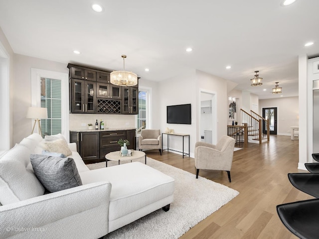 living room with light hardwood / wood-style flooring, a notable chandelier, and bar