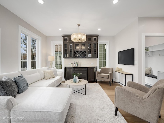 living room featuring bar, light hardwood / wood-style flooring, and an inviting chandelier