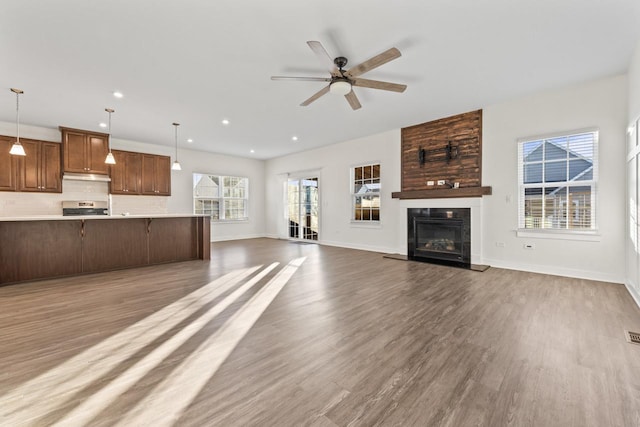 unfurnished living room featuring a large fireplace, ceiling fan, and wood-type flooring