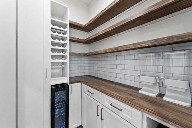 kitchen with butcher block counters, decorative backsplash, white cabinets, and beverage cooler