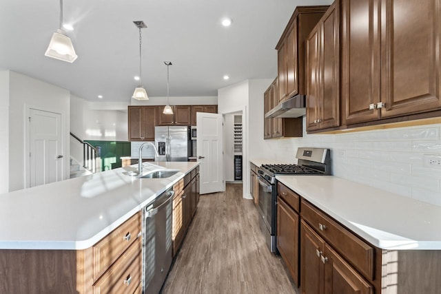 kitchen with a center island with sink, appliances with stainless steel finishes, pendant lighting, and sink