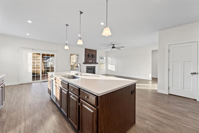 kitchen featuring decorative light fixtures, sink, a kitchen island with sink, ceiling fan, and dark brown cabinetry