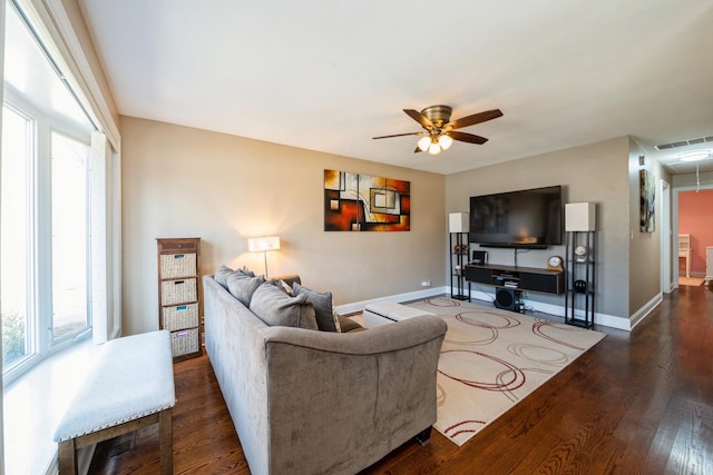 living area with visible vents, baseboards, attic access, wood finished floors, and a ceiling fan