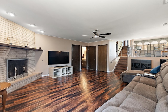 living room with ceiling fan, dark hardwood / wood-style flooring, and a brick fireplace