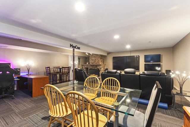 dining room with dark carpet and a stone fireplace