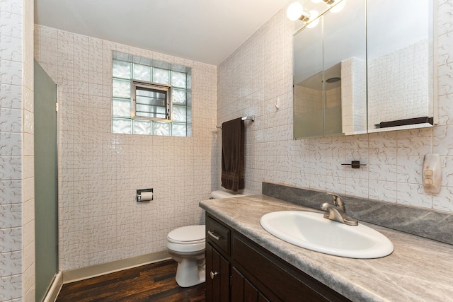 bathroom featuring vanity, a shower with shower door, toilet, tile walls, and wood-type flooring