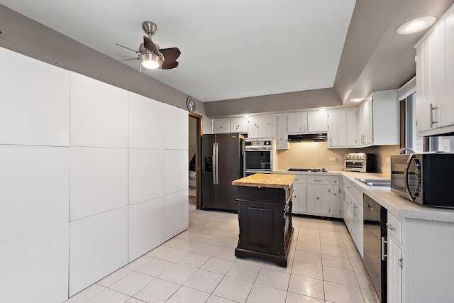 kitchen featuring ventilation hood, a center island, white cabinetry, and stainless steel appliances