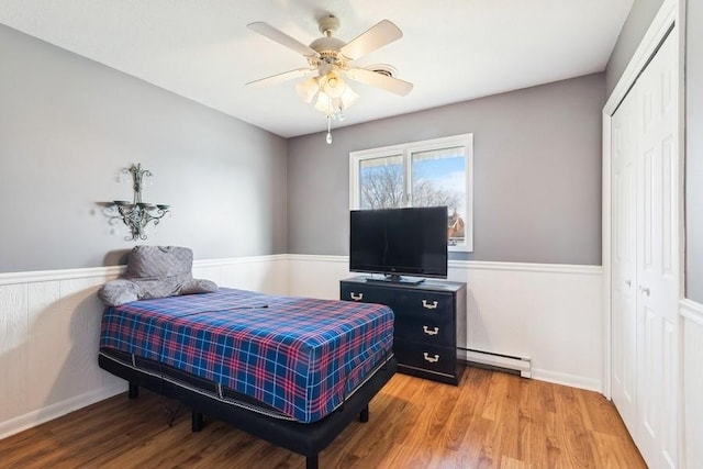 bedroom featuring ceiling fan, a closet, a baseboard radiator, and hardwood / wood-style flooring