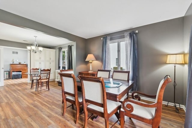 dining space with light hardwood / wood-style flooring, a healthy amount of sunlight, and a notable chandelier