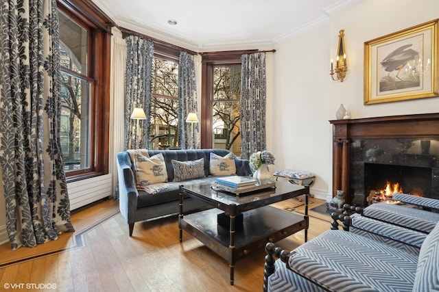 living area featuring crown molding, a fireplace, and light hardwood / wood-style floors