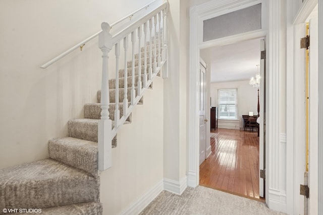 stairway with an inviting chandelier and wood-type flooring