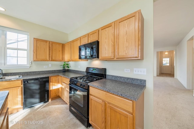 kitchen featuring a healthy amount of sunlight, sink, black appliances, and light carpet