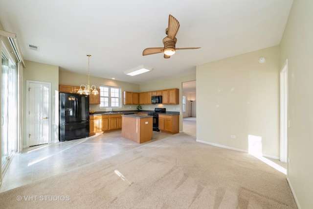 kitchen featuring a center island, black appliances, ceiling fan with notable chandelier, sink, and decorative light fixtures