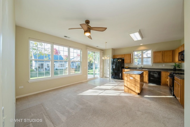 kitchen featuring pendant lighting, a kitchen island, a healthy amount of sunlight, and black appliances