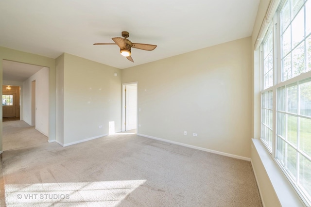 carpeted empty room with ceiling fan and plenty of natural light